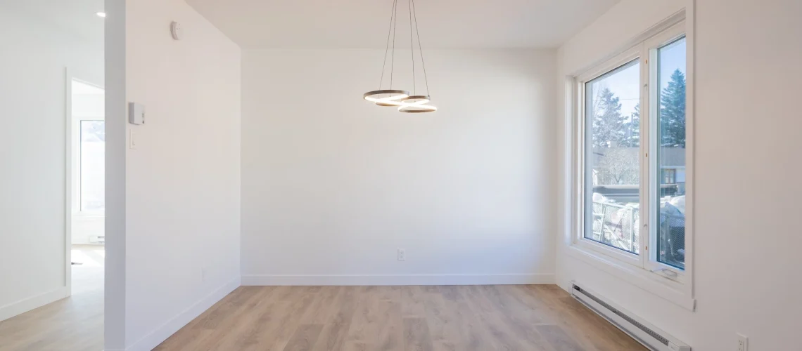 Salon rénové avec des finitions élégantes, des couleurs neutres et un éclairage moderne pour un espace lumineux.