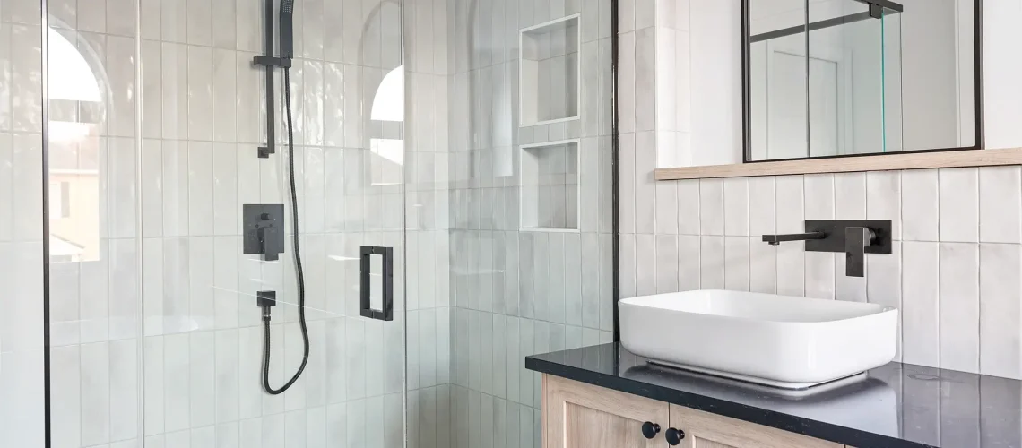 Salle de bain moderne avec un mur accent en carreaux, une grande baignoire et des finitions de qualité.