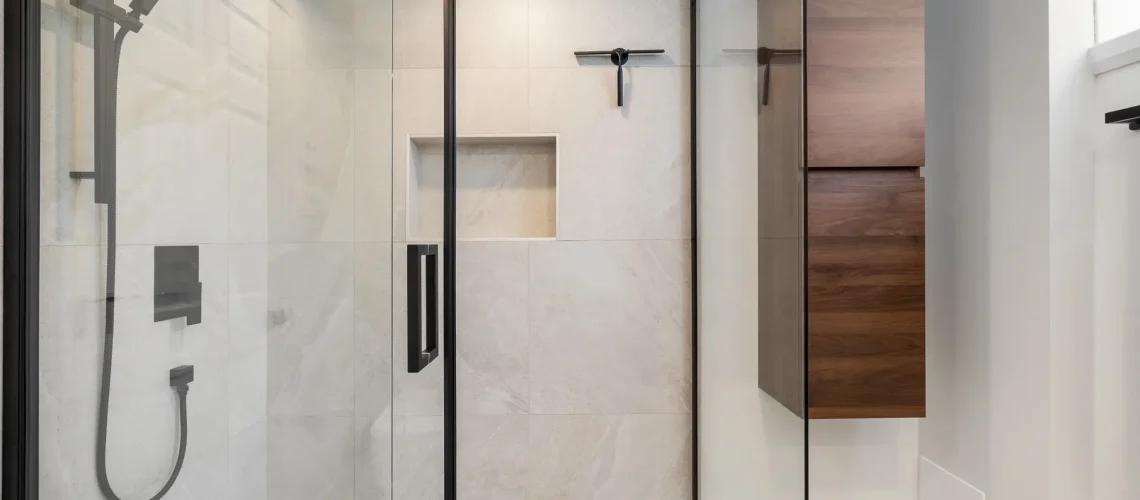 Salle de bain rénovée avec des finitions métalliques, une grande douche et un meuble vasque moderne.
